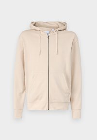 Bež hoodie sa zatvaračem napravljen od mekog materijala, koji sadrži kapuljaču, uže za podešavanje i dva prednja džepa. Rukavi i donji rub su rebrasti.