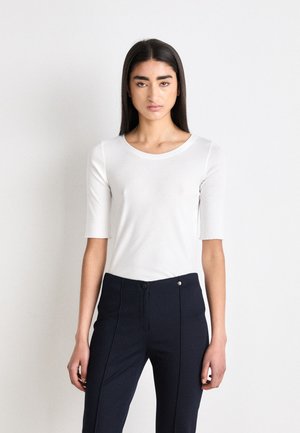 Witte aansluitende top met korte mouwen en een ronde hals, gecombineerd met marineblauwe tailored broek met een knoopsluiting en verticale naaddetails.