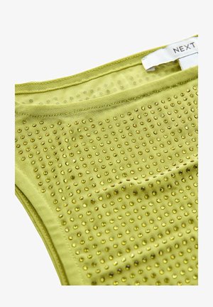 Roheline kangas, millel on tekstuuriga pind ja väikesed läikivad kuldsed nupud, mis on paigutatud ruudustikku. Sildiga, mis on kinnitatud ülemisse serva.