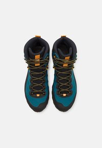 Bottes de randonnée montantes en teal et noir. Embout renforcé, lacets texturés et accents oranges vifs. Matériau durable avec une semelle robuste.