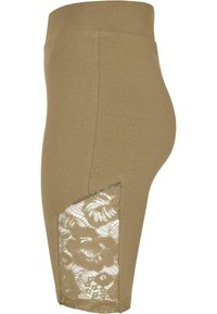 Tanskleurige legging met een hoge taille, voorzien van een zijpaneel met kant en bloemenpatronen. Zachte stof met een aangesloten silhouet.