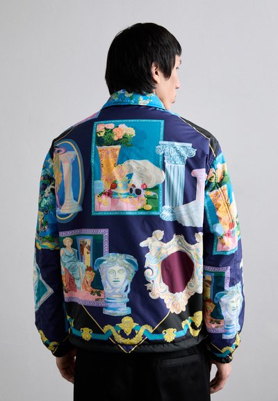 Multicolored bomber jacket featuring classical art motifs, floral patterns, and ornamental designs on a dark background. Satin finish.