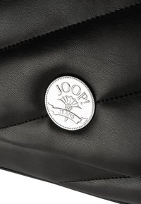 Czarna torebka z fakturowanej skóry z okrągłym, srebrnym klipsem z logo "JOOP! JEANS" i dekoracyjnym przeszyciem na powierzchni.