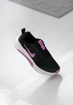 Sort sportssko med pink Nike-swoosh og accenter, hvid sål og sorte snørebånd på en lysegrå overflade.