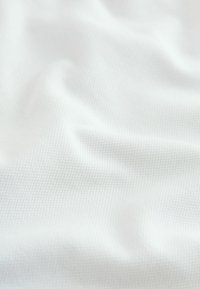 Hvidt tekstureret stof med et subtilt ternet mønster, draperet for at vise dets blødhed og fleksibilitet, der fremhæver dets glatte overflade og lette kvalitet.