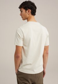 Světle béžové tričko s krátkým rukávem a kulatým výstřihem, vyrobené z měkké bavlny. Má hladkou texturu a uvolněný střih.