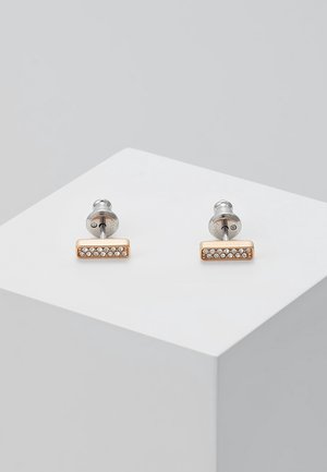 Paire de petites boucles d'oreilles rectangulaires en or avec une rangée de cristaux clairs, présentées sur un cube blanc sur un fond gris.
