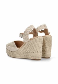 Sandalias de cuña beige con parte superior de tela texturizada, correa de tobillo ajustable y plataforma estilo yute trenzado. Suela plana con costuras decorativas.