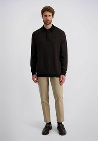 Braun gemustertes langärmliges Poloshirt mit schwarzem Kragen und drei Knöpfen, kombiniert mit beigen Hosen und dunklen Schuhen. Glatte Textur.