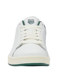 Sneaker alb K-Swiss văzut din față, cu șireturi albe, căptușeală interioară verde și un logo verde și alb pe limbă.