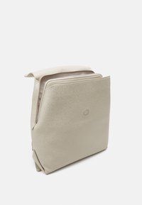 Beżowy plecak na suwak wykonany z teksturowanego materiału, z subtelnym wzorem logo i okrągłym akcentem na środku. Minimalistyczny design.