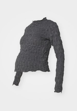 Temno siva dolga majica z dolgimi rokavi in strukturnimi, dvignjenimi listnatimi vzorci ter visokim ovratnikom, ki ima nekoliko krajši, oprijet kroj.