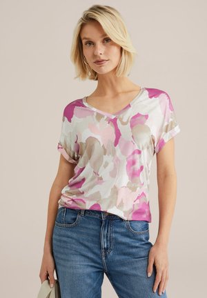 T-shirt col V avec un motif floral dans des nuances de rose, violet et beige, fabriqué à partir d'un tissu doux. Manches roulées et coupe décontractée.