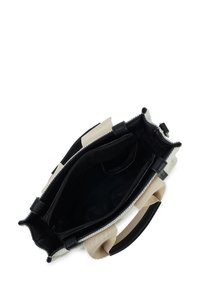 Klein beige en zwarte handtas met bovenrits, interne compartimenten en stoffen handvatten, gezien van bovenop op een witte achtergrond.