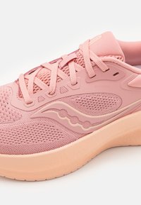 Pink athletic shoe with mesh upper, reinforced accents, thick rubber sole, and prominent brand logo on the side. Laces are flat and wide.