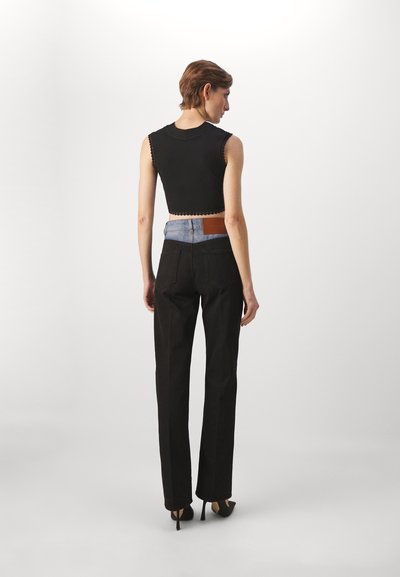 Top court noir avec des bords festonnés associé à un jean noir taille haute avec un panneau arrière bleu clair et une patch en cuir marron.