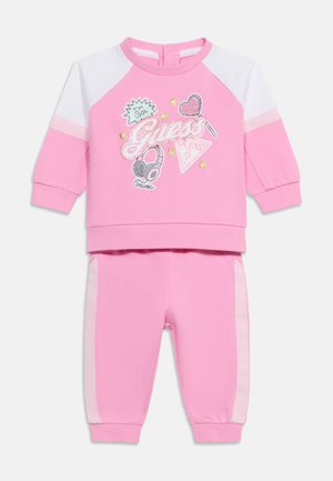 Completo per bambini con felpa e pantaloni rosa e bianchi con logo "Guess" glitterato, cuore, cuffie, stelle e scritta "I'm cool" sulla felpa.