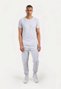 Lysegrå bomulds-T-shirt kombineret med matchende grå joggingbukser. Sættet har en klassisk pasform og ribstrikkede ærmeafslutninger, suppleret med hvide sneakers.