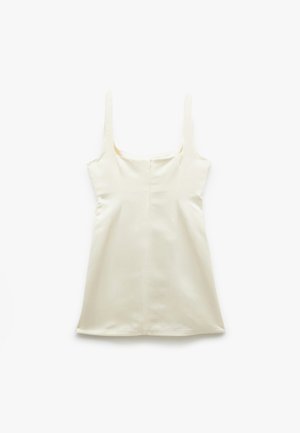 Robe sans manches, de couleur crème, avec un décolleté carré, fabriquée dans un tissu lisse. Présente une coupe droite et une fermeture éclair dissimulée dans le dos.