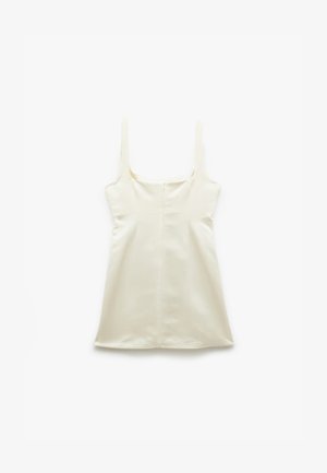Robe sans manches, de couleur crème, avec un décolleté carré, fabriquée dans un tissu lisse. Présente une coupe droite et une fermeture éclair dissimulée dans le dos.