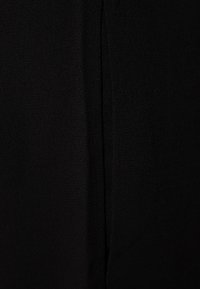 Gros plan d'un tissu noir texturé avec une couture ou un pli vertical central courant au milieu.