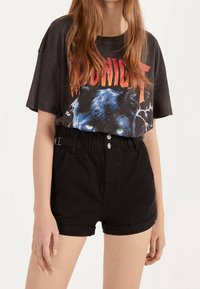 Grafisk svart T-shirt med en blå panterdesign med gröna ögon och ordet "MIDNIGHT" i röd text, tillsammans med högmidjade svarta shorts.