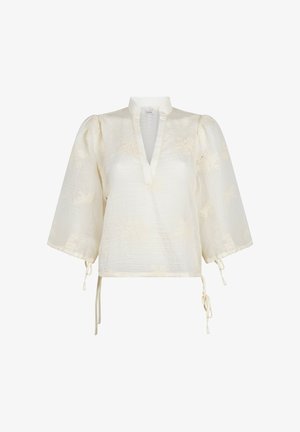 Blouse crème avec manches bouffantes trois-quarts, col en V, motif floral subtil et détails noués aux manches et à l'ourlet.