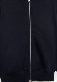 Hanorac negru cu fermoar în față, fermoar argintiu și două buzunare frontale, realizat dintr-un material moale, cu tiv striat.