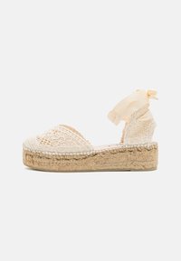Beige espadrille sandal with woven upper, lace ankle tie, and jute platform sole. Intricate lace pattern detail on the toe area.