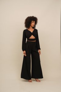 Black two-piece outfit featuring a cropped long-sleeve top with a twist front and high-waisted wide-leg trousers; smooth fabric, minimal detailing.