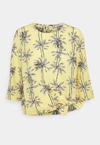 Blusa gialla con un motivo di palme in bianco e nero; presenta una vestibilità morbida, maniche a tre quarti e un dettaglio anteriore annodato.