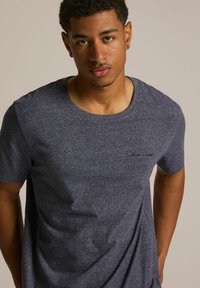 Granatowa koszulka z krótkim rękawem o okrągłym dekolcie, wykonana z teksturowanej tkaniny z delikatnymi włoskami i małym logo na klatce piersiowej.
