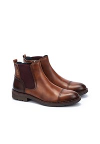 Botas de tobillo de cuero marrón con paneles laterales elásticos y punta redonda. Presenta una suela texturizada y un minimalismo en la costura decorativa.