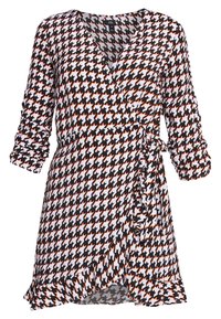 Musta, valkoinen ja oranssi houndstooth-kietaisumekko, jossa on 3/4-pituiset rypytetyt hihat ja röyhelöhelma, sidottuna vyötärölle oikealla puolella.
