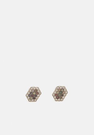 Boucles d'oreilles hexagonales ornées de pierres multicolores montées sur une base dorée, entourées de petits cristaux clairs. Détail de surface texturée visible.