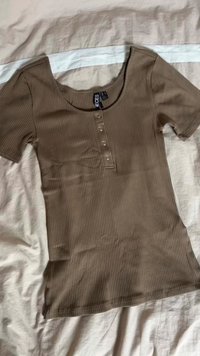 Brown ribbed t-shirt with short sleeves, wide neckline, and four button placket at the front. Soft fabric with a smooth texture.