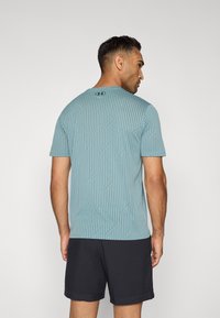 Camisa de manga corta para hombre en azul claro con rayas texturizadas y un escote redondo. La parte trasera presenta el logo de la marca y detalles en patrón de zigzag.
