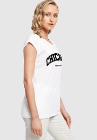 Witte t-shirt met vet zwart tekst "CHICAGO" en "MERCH" in een gebogen ontwerp. Korte mouwen en zachte katoen materiaal. Casual pasvorm.