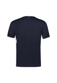 T-shirt à manches courtes bleu marine avec un col rond, fabriqué en tissu doux, comportant un petit accent rouge et blanc à l'arrière.