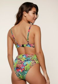 Costume da bagno a due pezzi con una stampa tropicale colorata che presenta vivaci tonalità di verde, rosa e blu. Spalline regolabili e chiusura con gancetto sul retro.