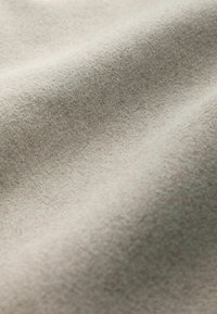 Licht beige stof met een zachte, textuurachtige oppervlakte, voorzien van een gladde, iets fuzzy uitstraling en subtiele kleurvariatie.