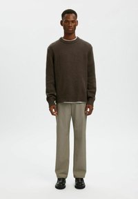 Maglione a maglia marrone scuro con colletto e orlo a coste, abbinato a pantaloni grigi e scarpe nere. Design semplice e dallo stile rilassato.