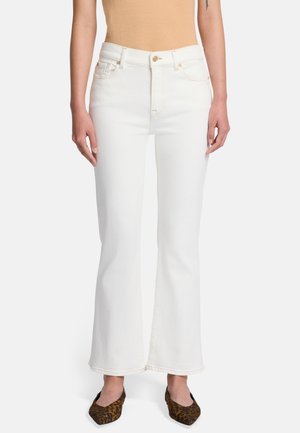 Weiße Jeans im Flared-Style mit hoher Taille, dezenten Nähten und klassischem Fünf-Taschen-Design, kombiniert mit spitzen Ballerinas im Leopardenmuster.