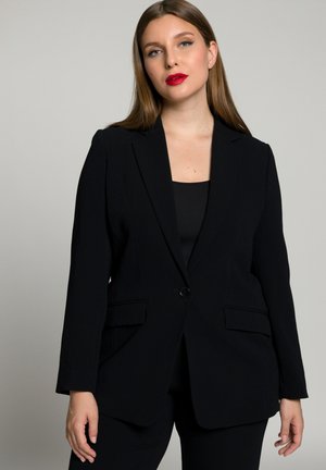 Černý přizpůsobený blazer vyrobený z hladkého materiálu, s jednobarevným zapínáním na knoflík, klopovými límci a předními kapsami. Upravena strukturovaná silueta.