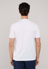 Camiseta blanca de cuello redondo hecha de algodón suave, con mangas cortas y un corte regular. Textura lisa sin patrones ni acentos visibles.
