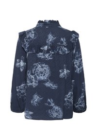 Mörkblå blus med blommönster i ljusblått. Har volangkrage och volanger vid ärmarna, långa ärmar och en avslappnad passform. Strukturerad tyg.