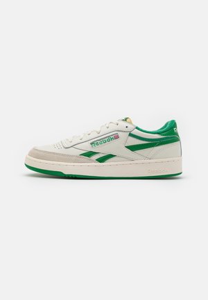 White and green low-top Reebok sneaker with textured sole, suede toe cap, and logo detailing on side and heel.