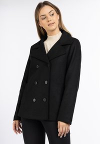 Black double-breasted coat with large buttons, wide lapels, and a textured fabric. Features side pockets and a relaxed fit.