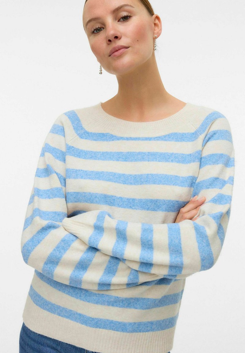 Pull rayé en crème avec des rayures bleu clair et bleu foncé, doté d'un col rond et d'une texture tricot douce. Manches longues.