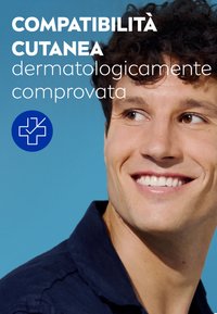Primo piano di un uomo con capelli corti e ricci marroni, che indossa una camicia blu scuro, sorridente su uno sfondo celeste chiaro uniforme.